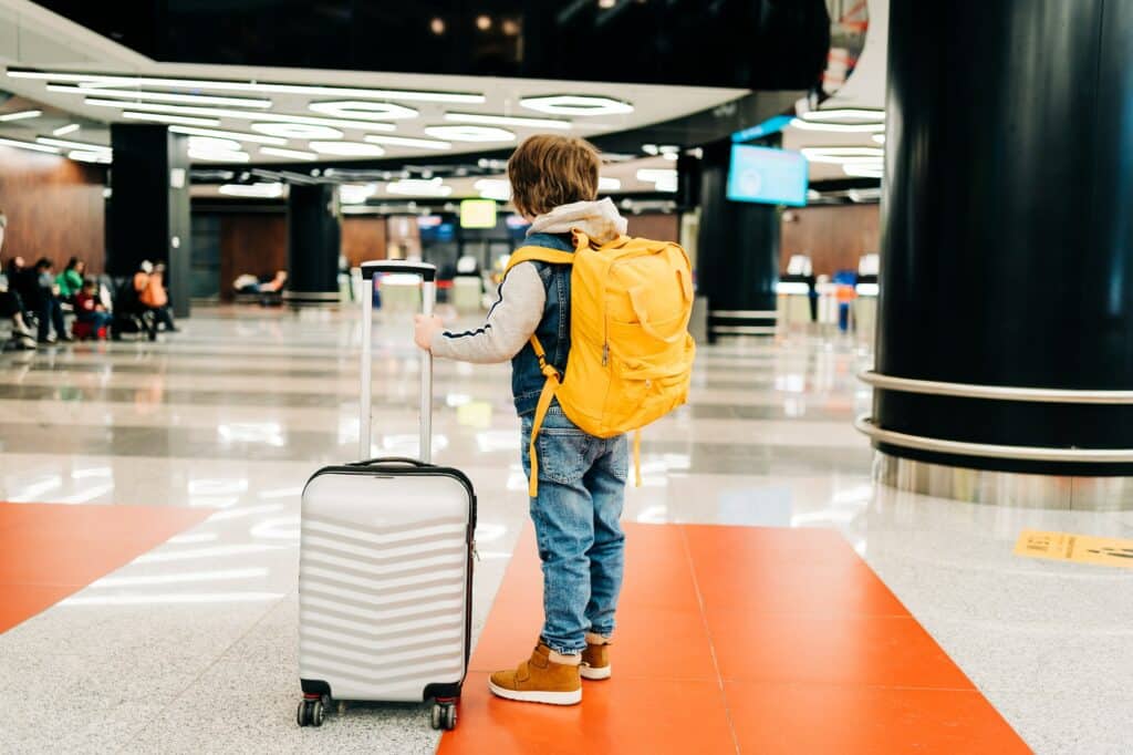 Child kid boy with backpack and suitcase in airport.